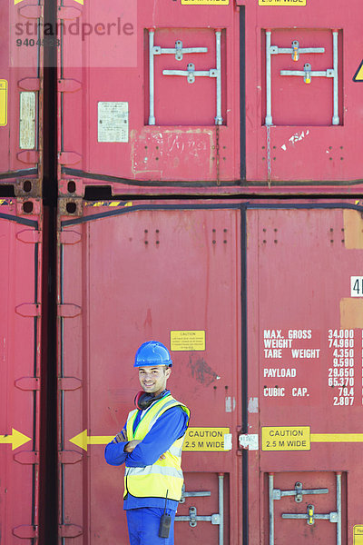 Arbeiter lächelt in der Nähe von Frachtcontainern