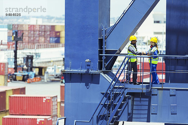 Arbeiter und Geschäftsmann beim Händeschütteln am Ladekran