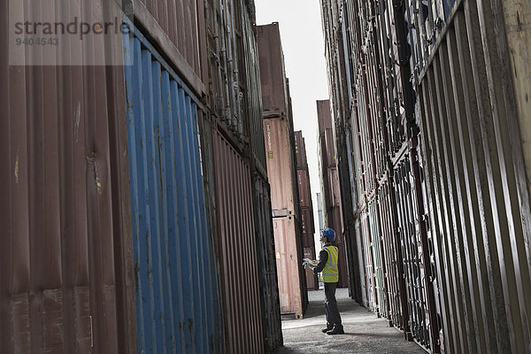 Arbeiter steht zwischen Frachtcontainern