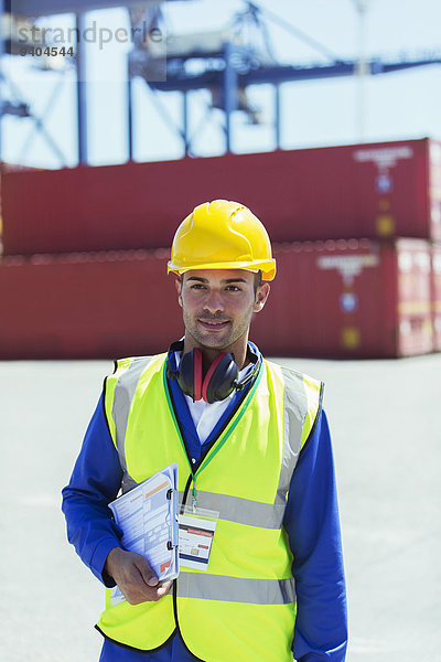 Arbeiter mit Klemmbrett in der Nähe von Frachtcontainern