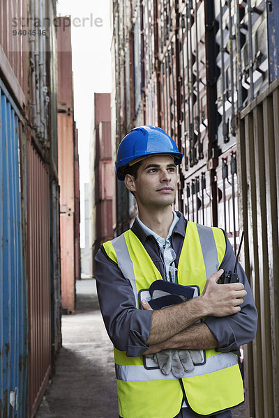 Arbeiter steht zwischen Frachtcontainern