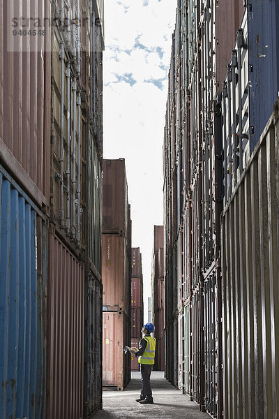 Arbeiter steht zwischen Frachtcontainern