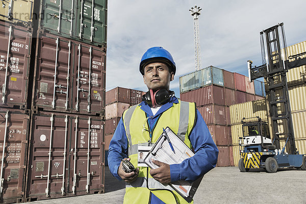 Arbeiter hält Zwischenablage in der Nähe von Frachtcontainern