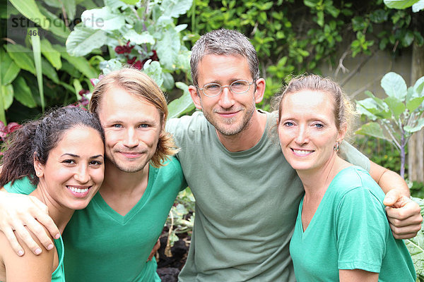 Porträt von vier Männern und Frauen in grünen T-Shirts im Garten