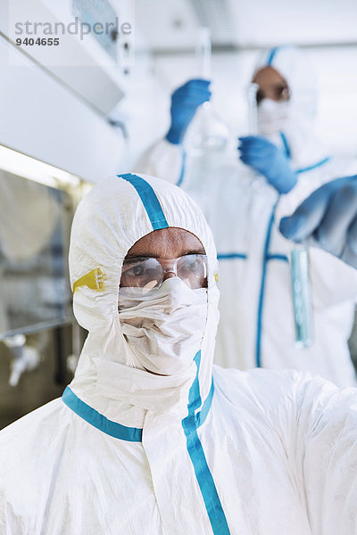 Wissenschaftler im Clean Suit untersucht Reagenzglas im Labor
