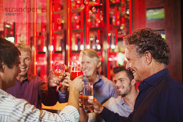 Fünf lächelnde Männer erheben Toast in der Bar