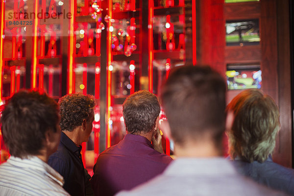 Rückansicht einer Gruppe von Männern  die in der Bar fernsehen.