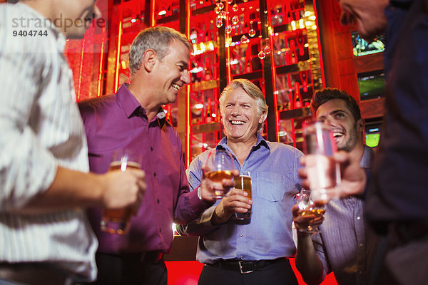 Gruppe lächelnder Männer bei einem Drink in der Bar