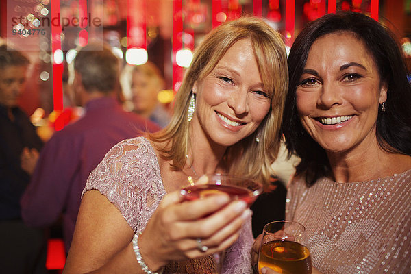 Porträt von lächelnden  reifen Frauen  die in der Bar trinken.