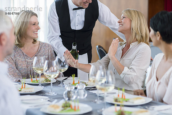 Kellnerin  die der Kundin am Restauranttisch Wein anbietet  Frau  die sich weigert.