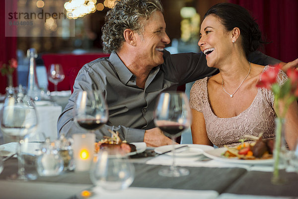 Glückliches reifes Paar am Restauranttisch sitzend  Weinglas im Vordergrund
