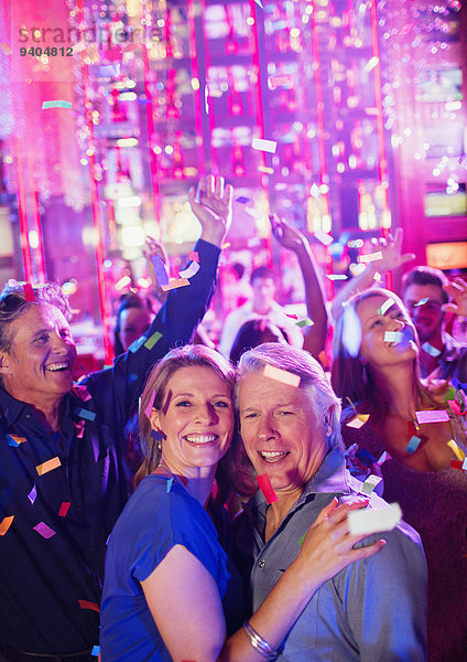 Konfetti  die auf lächelnde reife Menschen fallen  die im Nachtclub tanzen.