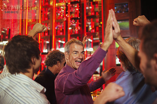 Männer  die sich im Nachtclub gegenseitig hochleben.