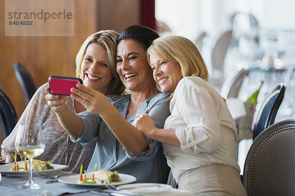 Drei reife Frauen  die Selfie im Restaurant nehmen.