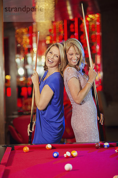 Zwei reife Frauen lachen und spielen Pool im Nachtclub