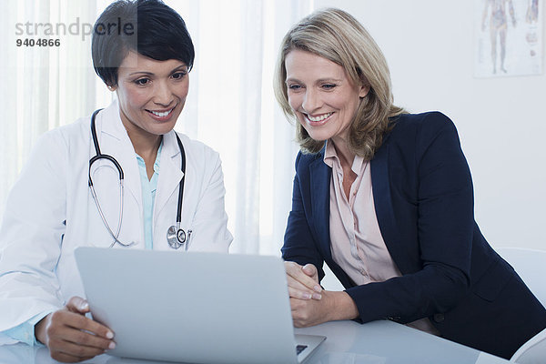 Arzt und Patient mit Laptop im Krankenhausbüro