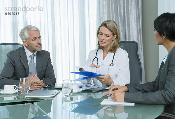 Ärztin  Mann und Frau beim Gespräch am Tisch im Konferenzraum
