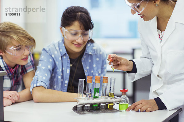 Lehrer und Schüler im Chemieunterricht  mit Schutzbrille und Blick auf Reagenzgläser