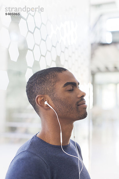 Porträt eines jungen Geschäftsmannes  der Musik über Kopfhörer hört