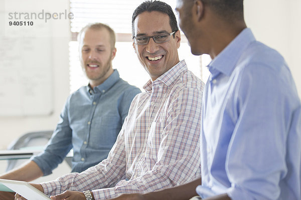 Drei lächelnde Männer  die zusammen im Büro arbeiten.
