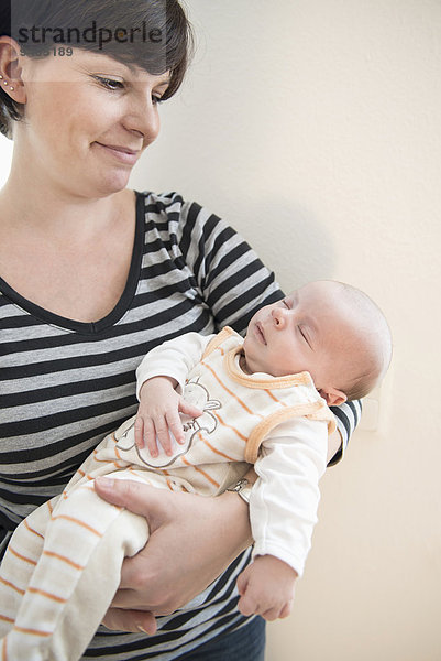 Mother holding her newborn baby in her arms  smiling