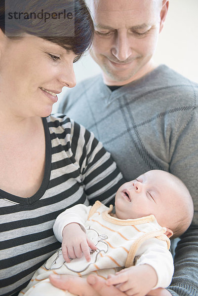 Parents holding their baby boy in arms  smiling