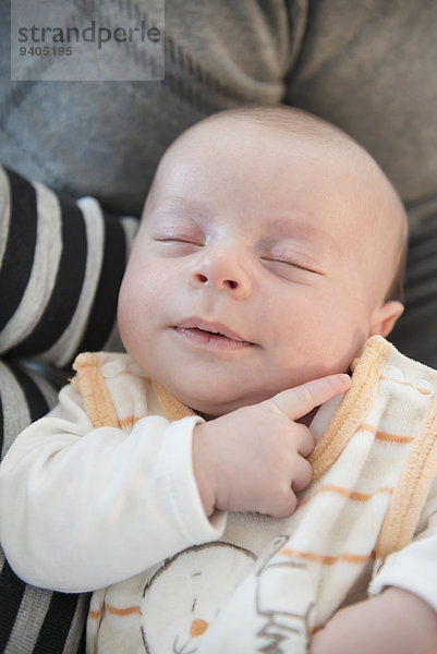 Baby boy sleeping safe in arms of his parents  close up