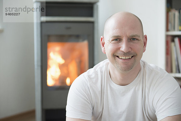 Portrait of man in his living room with fireplace  smiling