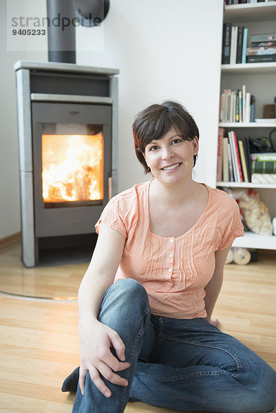 Portrait of woman sitting in his living room with fireplace  smiling