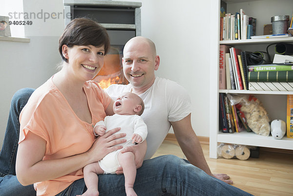 Portrait of parents with baby boy in living room  smiling