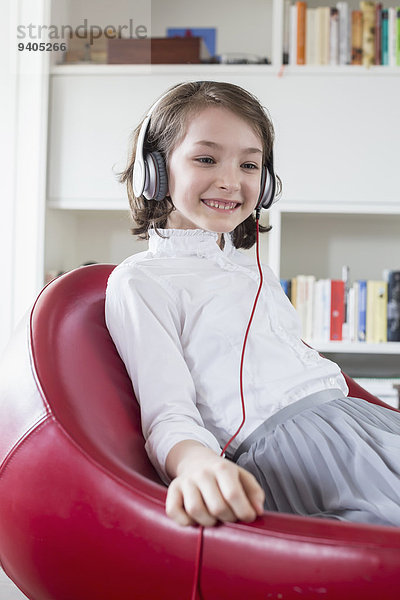 Girl sitting on chair with headset and listening music  smiling