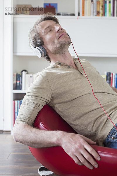 Man sitting on chair with headset and listening music