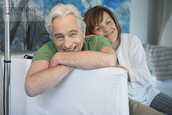Portrait of couple sitting on couch in living room  smiling