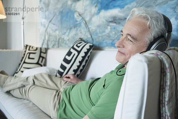 Mature man with headset sitting on couch  smiling