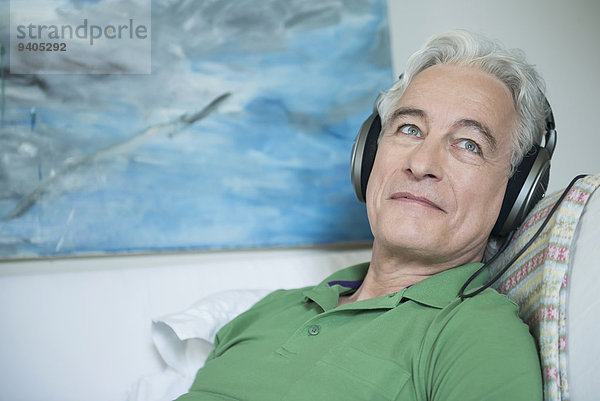 Mature man with headset sitting on couch  smiling