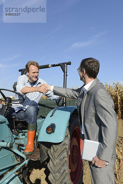 Kornfeld sitzend Hände schütteln Handschlag Geschäftsmann grüßen Traktor Bauer