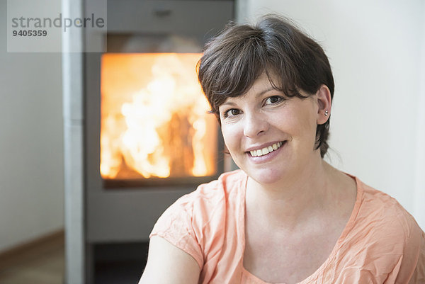 Portrait of woman in his living room with fireplace  smiling