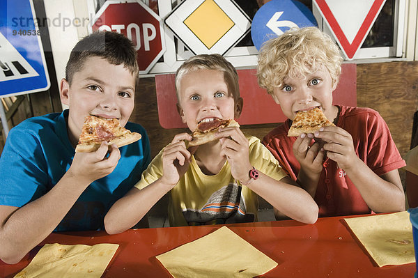 Three boys eating pizza at driver training area