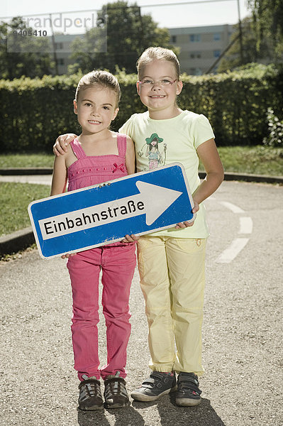 Two girls on driver training area holding traffic sign
