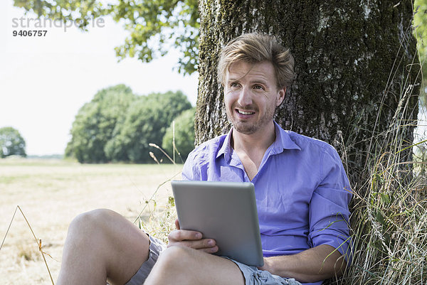 sitzend Mann Baum unterhalb Mittelpunkt Tablet PC Erwachsener