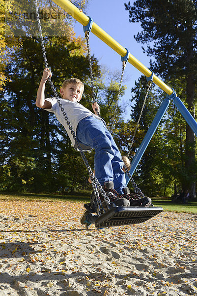 schaukeln schaukelnd schaukelt schwingen schwingt schwingend Junge - Person Spielplatz Schaukel