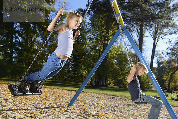 schaukeln schaukelnd schaukelt schwingen schwingt schwingend Junge - Person Spielplatz Schaukel