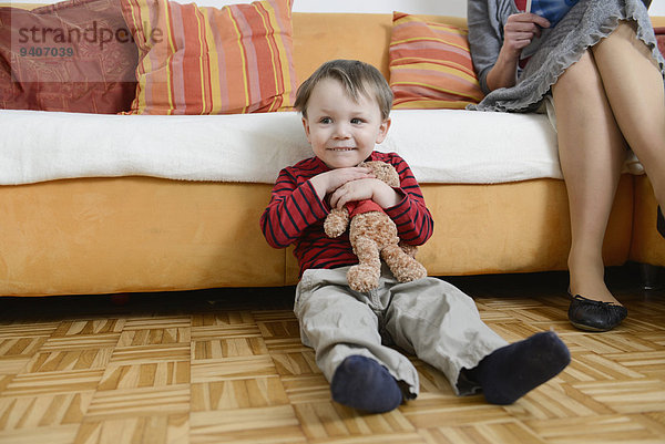 sitzend Boden Fußboden Fußböden lächeln Junge - Person Teddy Teddybär