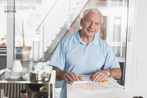 Interior zu Hause Senior Senioren benutzen Mann Taschenrechner lächeln