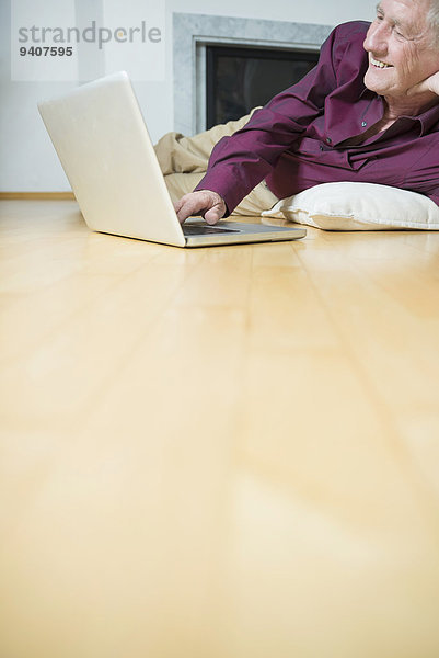 Senior Senioren benutzen Mann Notebook lächeln Zimmer Wohnzimmer