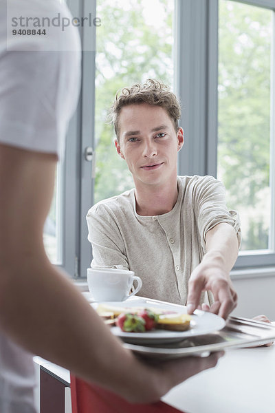 Mann Angebot lächeln Teller jung Frühstück