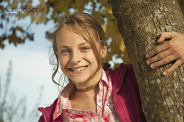 Portrait lächeln Baum halten Baumstamm Stamm Mädchen