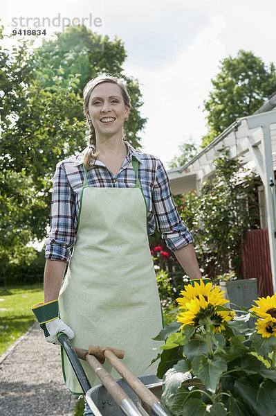 Portrait Frau schieben Schubkarre Garten