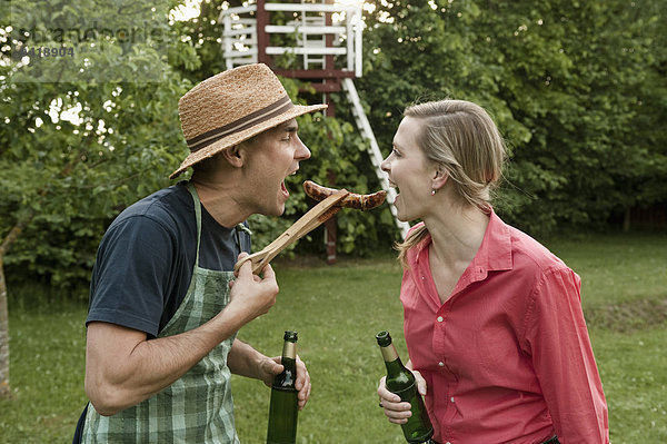 Frau Mann Wurst essen essend isst Grillparty