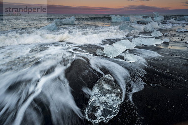 Eisbrocken am schwarzen Strand vom Meer umspült  Abendrot  bei Gletscherlagune Jökulsárlón  Vatnajökull-Gletscher  Austurland  Island